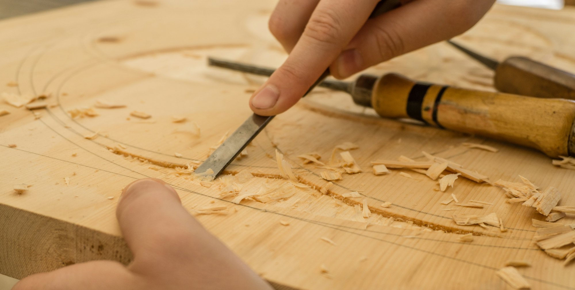Manos de artesano trabajando la madera con formón